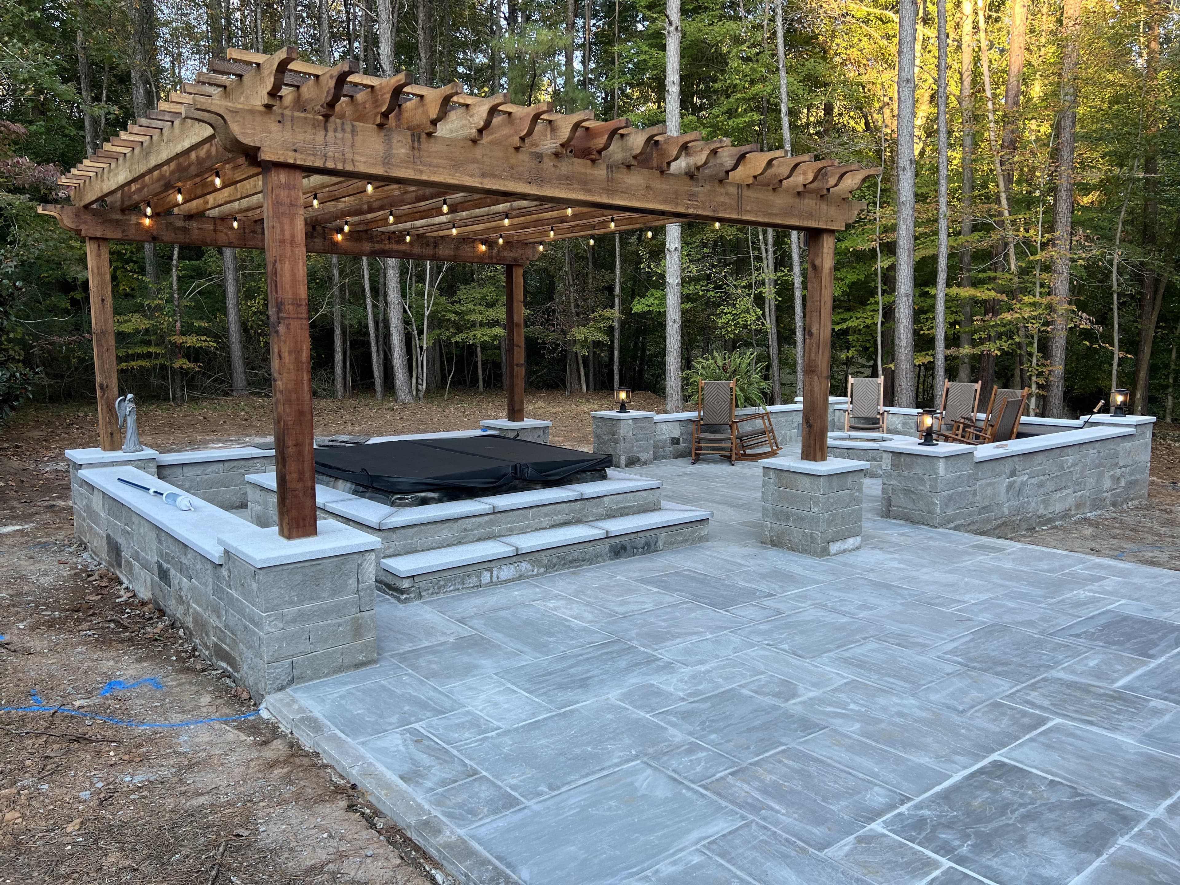 Precision Outdoor Construction - Custom pergola with string lights over stone patio and spa