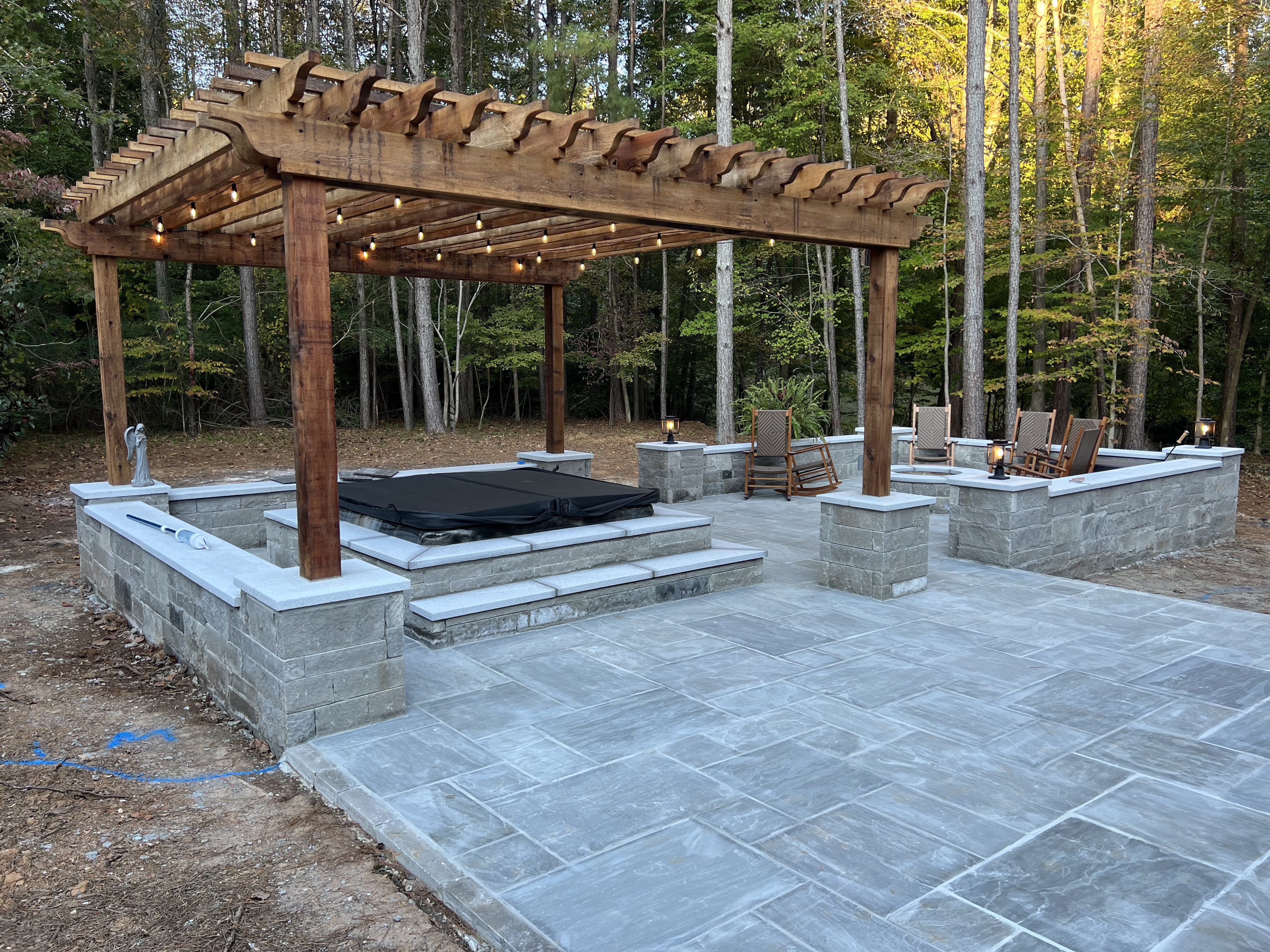 Precision Outdoor Construction - Custom pergola with string lights over stone patio and spa