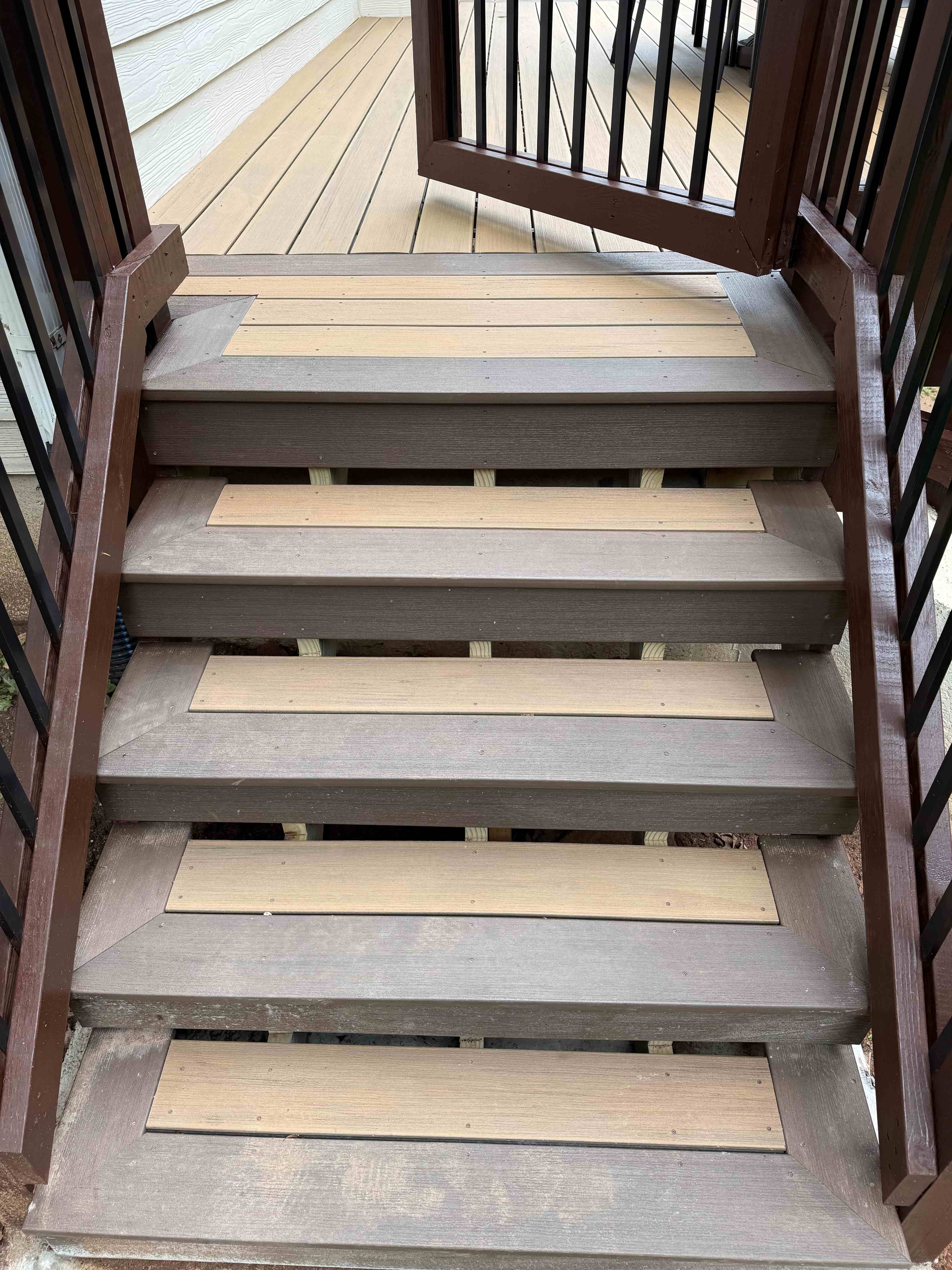 Two-tone composite deck stairs with contrasting treads and black balusters